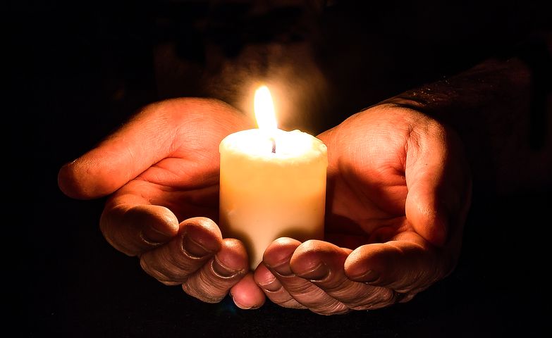 Lit candle in open hands