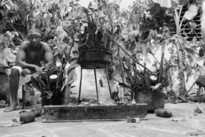 Man sitting barefoot and shirtless at his altar