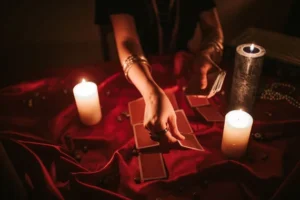 Woman laying cards with candles lit and red tablecloth on table