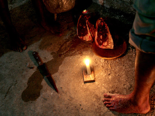 foot next to knife and two nkuyu or protection spirits with a candle lit